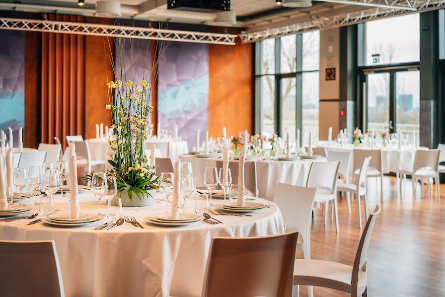 Veranstaltungsraum Rheinblick mit Runden Tischen und Stühlen. Die Tische sind festlich gedeckt.