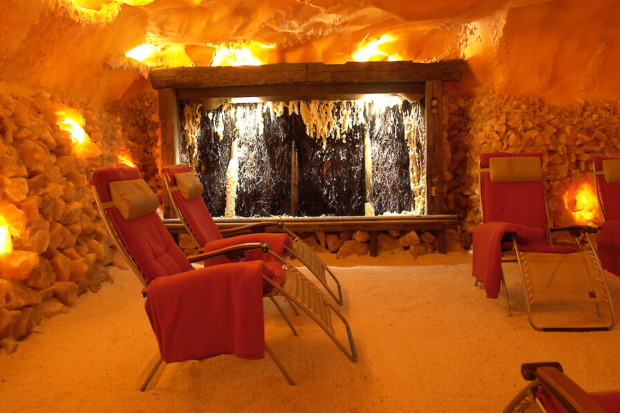Salzgrotte in orangenes Licht getaucht mit Liegestühlen.