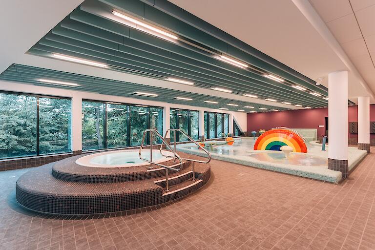 Kinderplanschbecken mit verschiedenen Attraktionen für Kinder sowie einem runden Warmwasserbecken.
