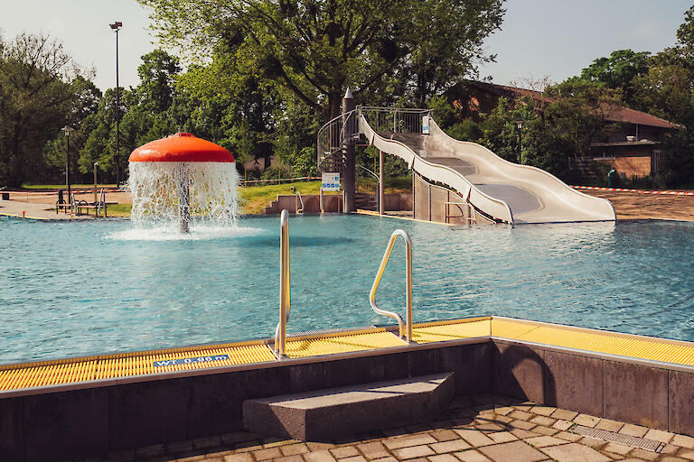 Mehrzweckbecken mit verschiedenen Attraktionen wie ein Wasserpilz und einer Breitrutsche.