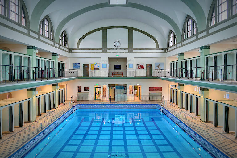 Schwimmhalle mit basilikale Gewölbe. Mehrzweckbecken sowie die Umkleiden, die auf zwei Etagen um das Becken herum verteilt sind.